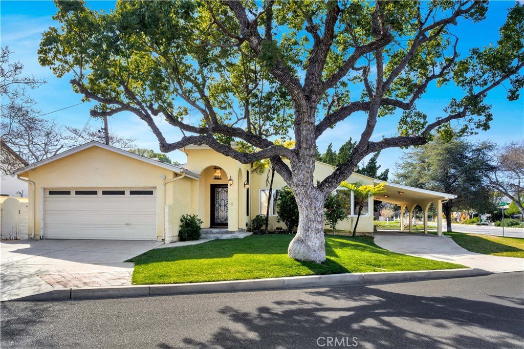 Yellow California single-story house with two-car garage, front tree, lawn, and covered porch.