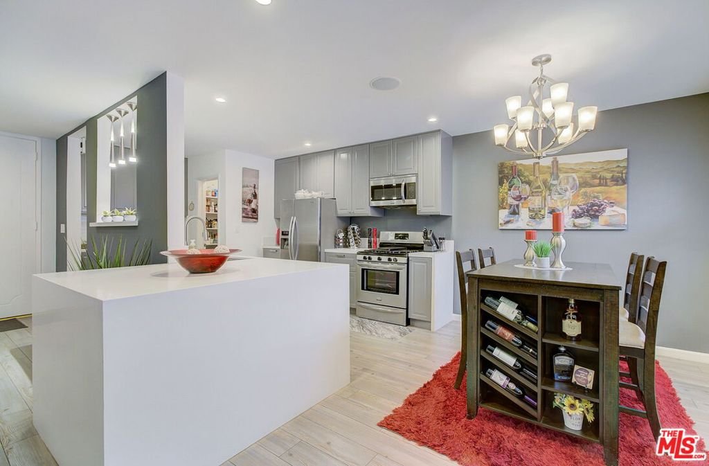 Modern luxury California kitchen with gray cabinets, stainless steel appliances, white island, and dining area.